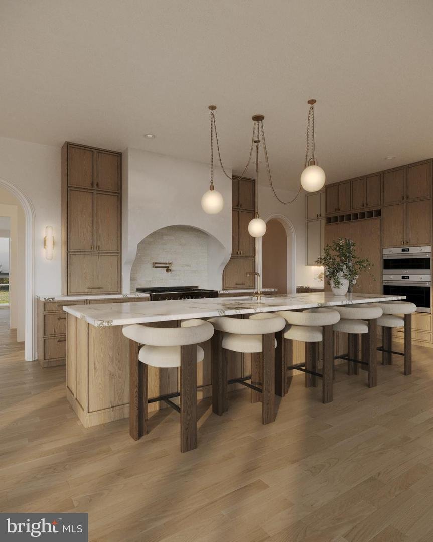 Rendering of the chef's kitchen with rift white oak cabinetry, a marble island, plaster range hood, and brass pendants